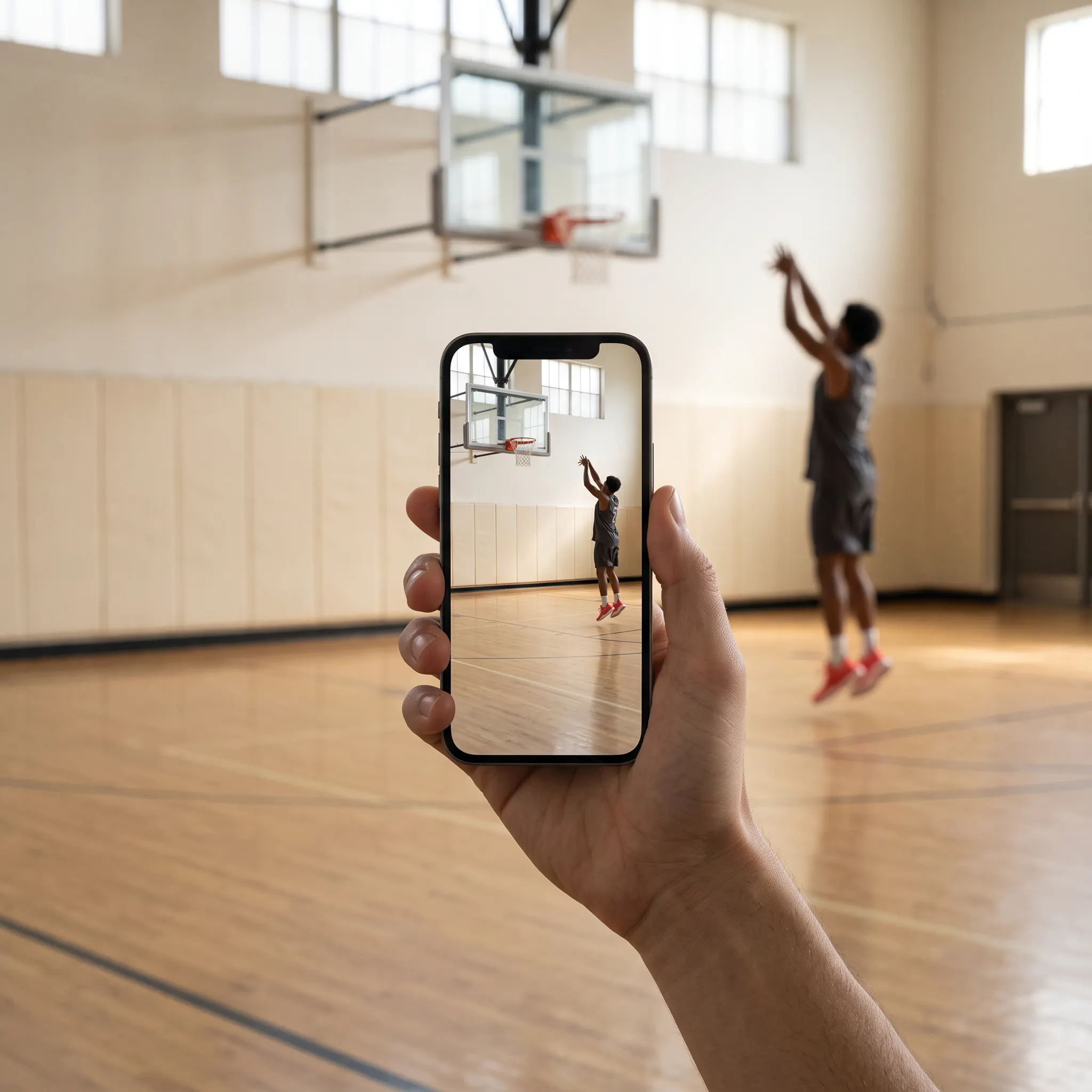 A phone filming a basketball player taking a shot